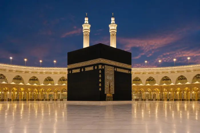 Majestic realistic photograph of the Kaaba inside the Masjid al-Haram in Makkah at dusk, calm soft light, dark navy sky, warm golden lamps on the arches, elegant symmetrical composition, no people in the foreground, no text, no signage